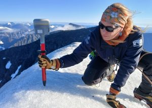 Frau mit GPS-Gerät auf vereistem Berggipfel
