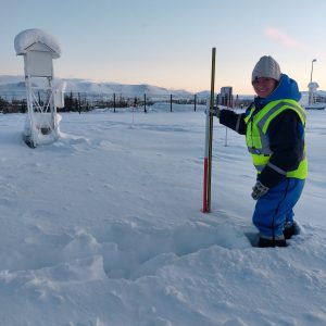 Frau mit Messstab in tiefem Schnee