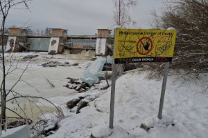 Gelbes Warnschild, im Hintergrund Fluttore und eine dicke Eisscholle